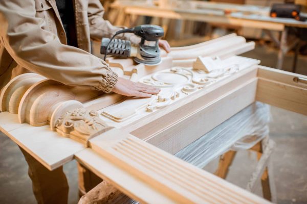 Handsome carpenter checks out carving quality of a joiner's product at the carpentry manufacturing