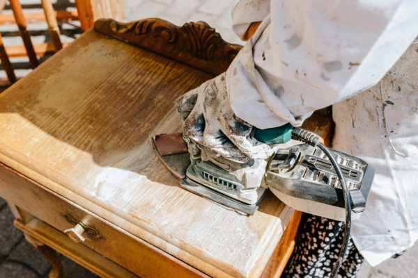 Unrecognizable carpenter using electric sander on old wooden furniture under restoration. carpentry business.